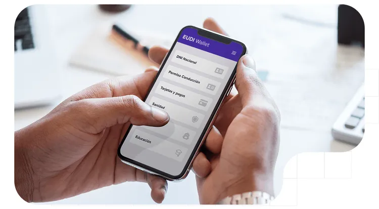 A close-up of hands holding a cell phone displaying the EUDI Wallet app's home screen.