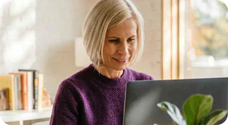 Professional woman smiling while working on her laptop in the office.