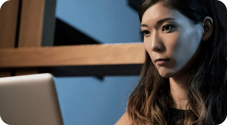 A woman checking her computer with concern after discovering suspicious activity on her accounts.