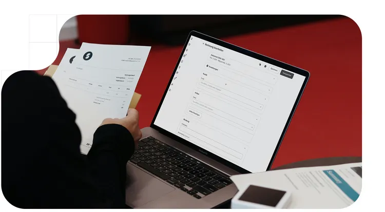 Person checking invoices for their business, on paper and on their pc